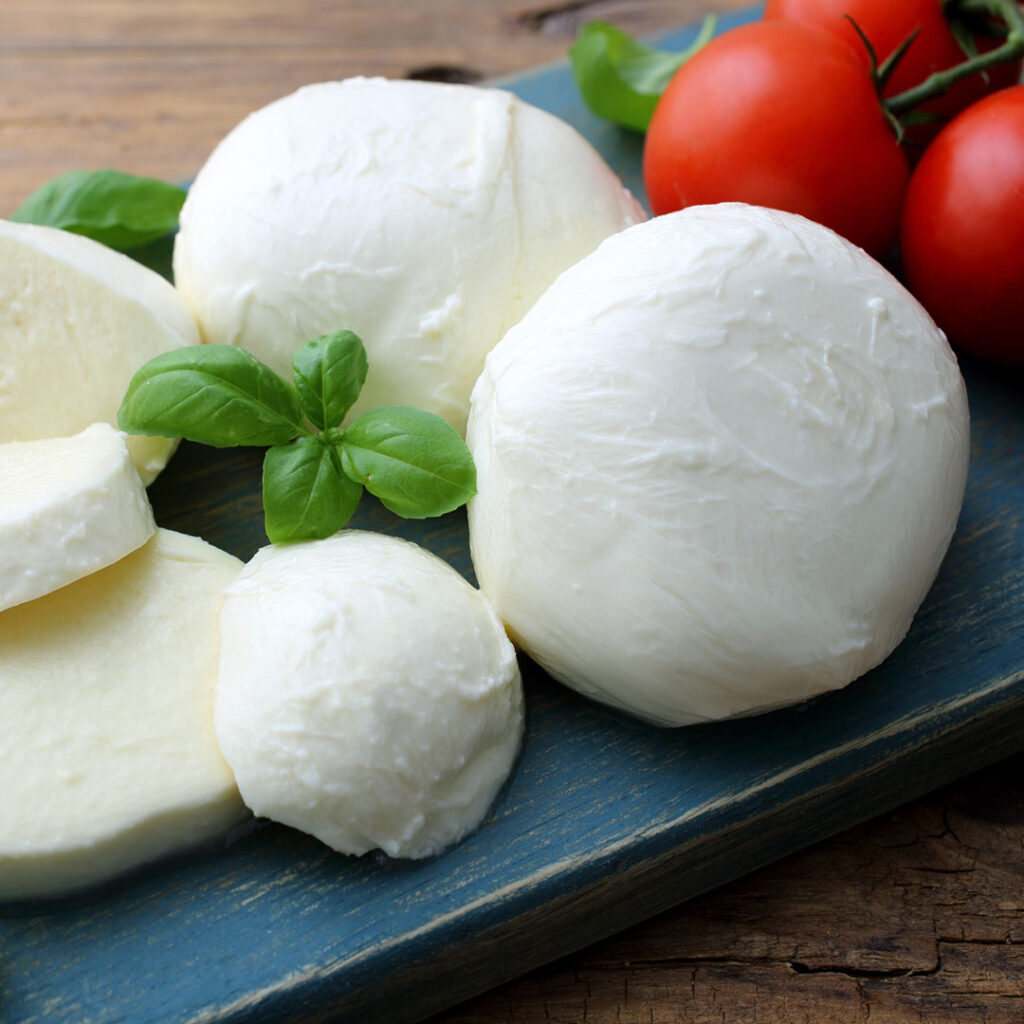 Das Bild zeigt mehrere Mozzarella Bällchen auf einem Holzbrettchen.